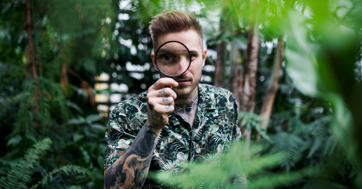 Man with magnifying glass searching in the jungle or forest