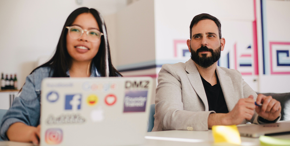 A man and a woman sat behind a laptop during a rebranding workshop