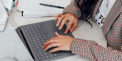 Close-up of woman in checked blazer typing on laptop