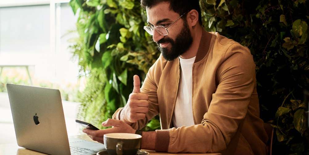 man in brown jacket sitting at laptop