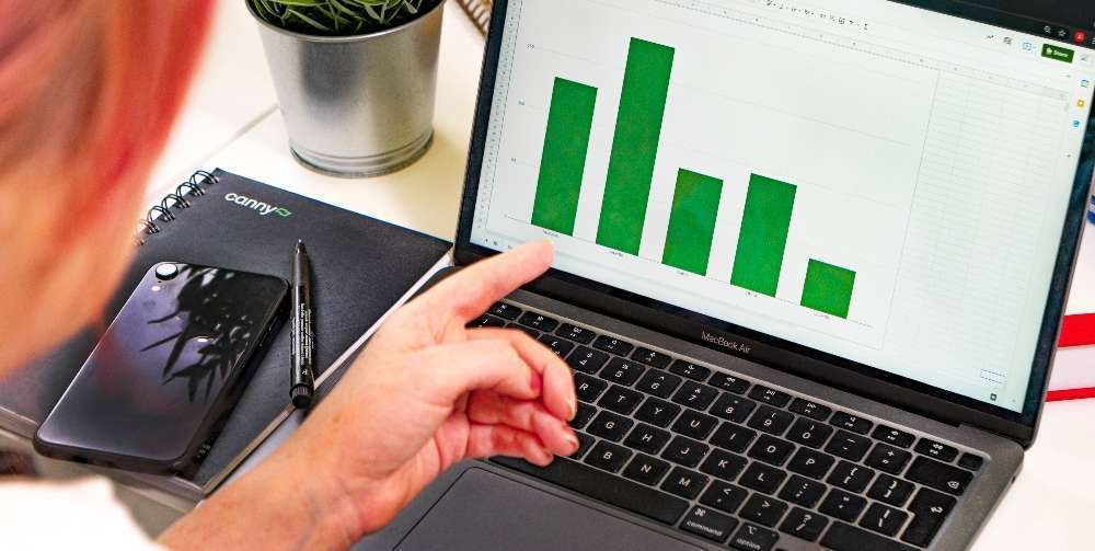 person pointing at bar chart on laptop screen