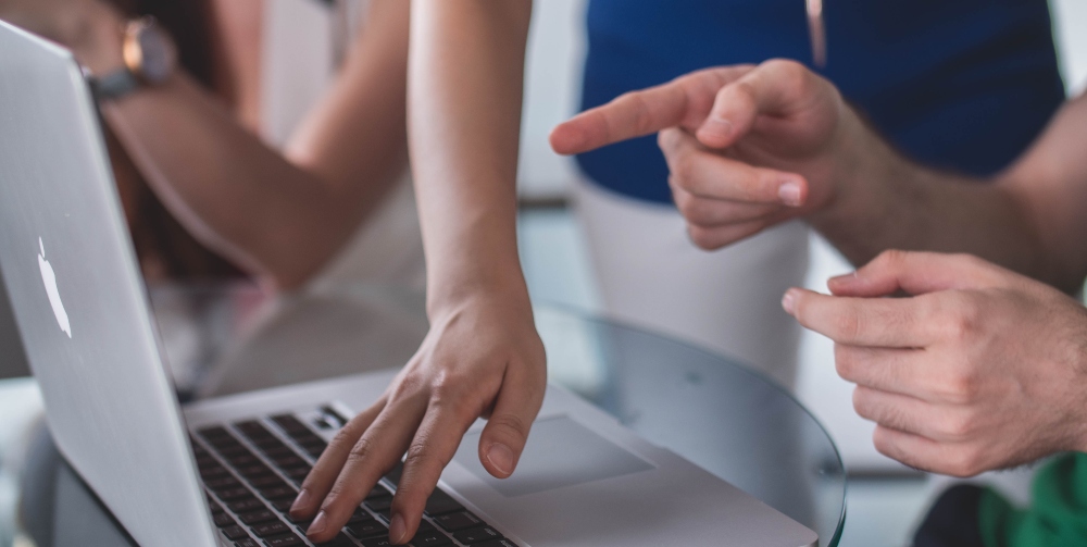 people pointing at laptop screen